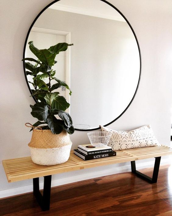 a mid-century modern space with a comfy bench and a large round mirror