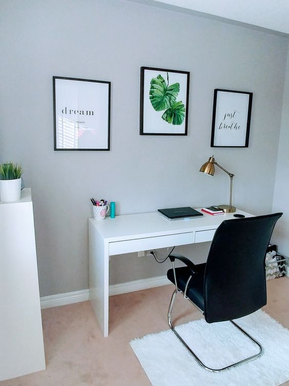 a modern working space with a Micke desk, a comfy black armchair and several artworks for a cool look