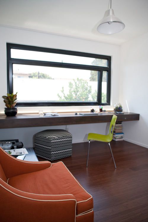 a modern black framed window and a thick wooden windowsill desk with a bold chair