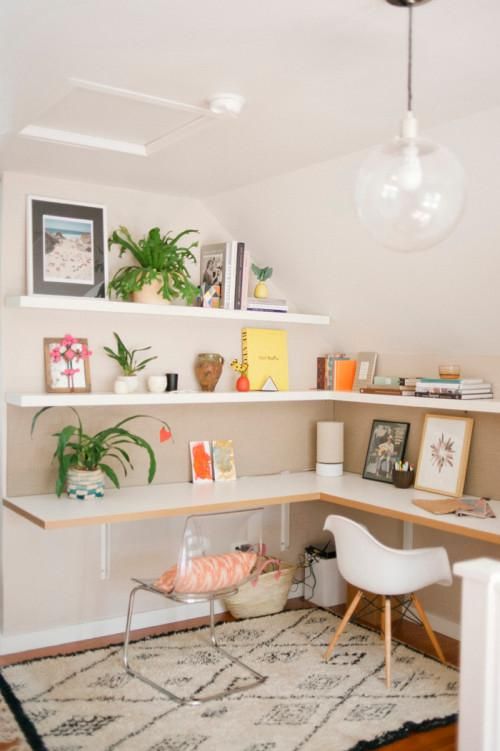 an attic corner with floating shelves and a matching desk that is large enough for two people