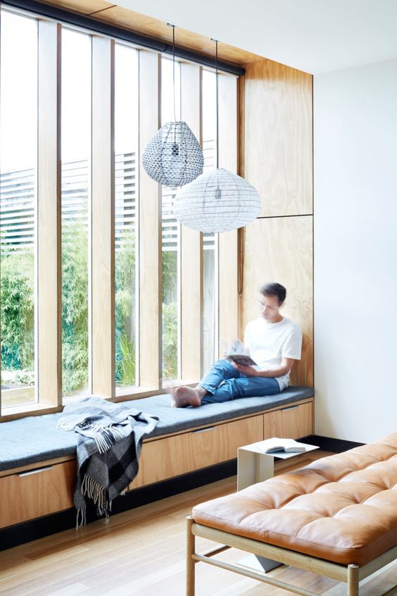 a comfy upholstered daybed with storage drawers and lamps over it