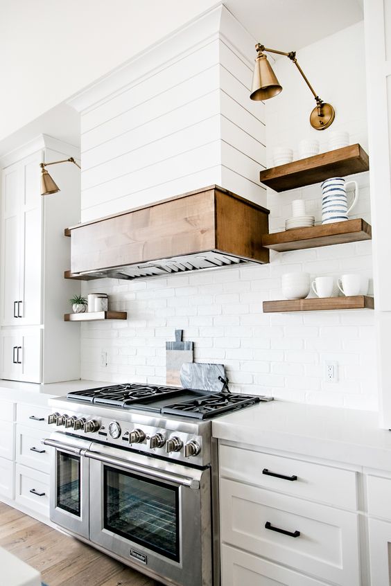 a stainless steel cooker and some brass lamps are nicely paired in the kitchen