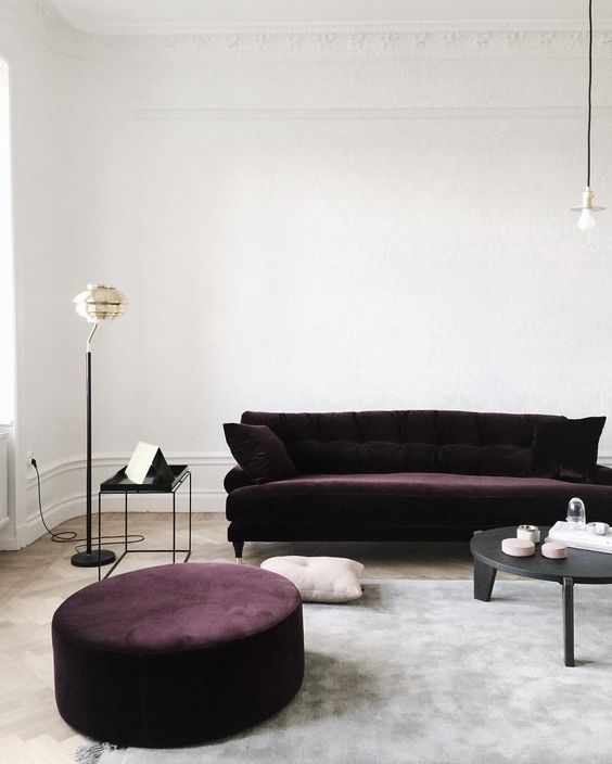 a dark aubergine sofa and ottoman make a bold statement and nearly make up the space