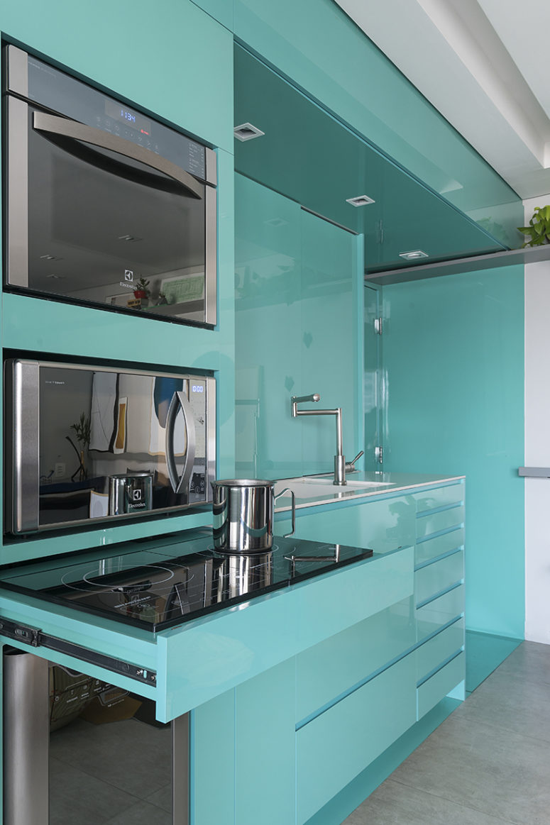 Sleek green surfaces make the kitchen stand out and visually separate this utility zone from the rest of the space Sleek green surfaces make the kitchen stand out and visually separate this utility zone from the rest of the space