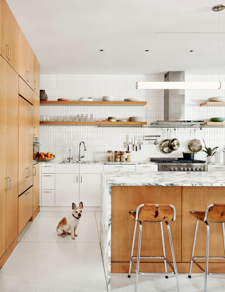 The kitchen united with the dining space is filled with light, done with white tiles and cabinets and some marble The kitchen united with the dining space is filled with light, done with white tiles and cabinets and some marble