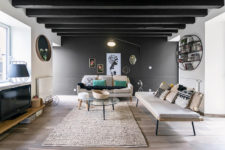 02 The living room is done with a black accent wall, black beams and modern furnishings plus artworks
