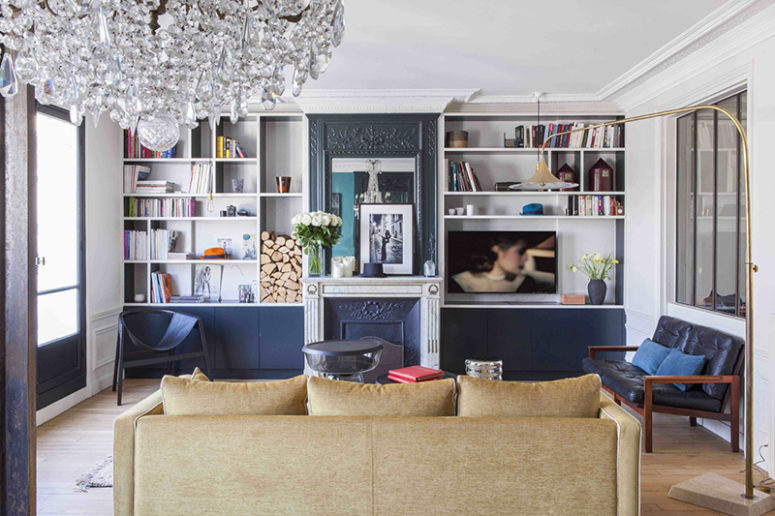 The living room is done with black ana navy touches, a faux fireplace, built in storage shelves and eye catchy furniture The living room is done with black ana navy touches, a faux fireplace, built-in storage shelves and eye-catchy furniture