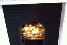 02 a faux fireplace clad with black brick and firewood and string lights inside looks super cool