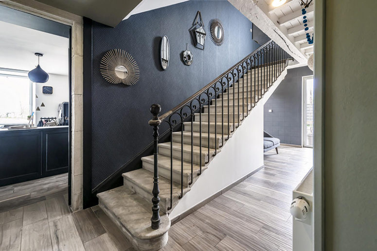 The hallway features an original marble staircase and a black wall plus some vintage mirrors