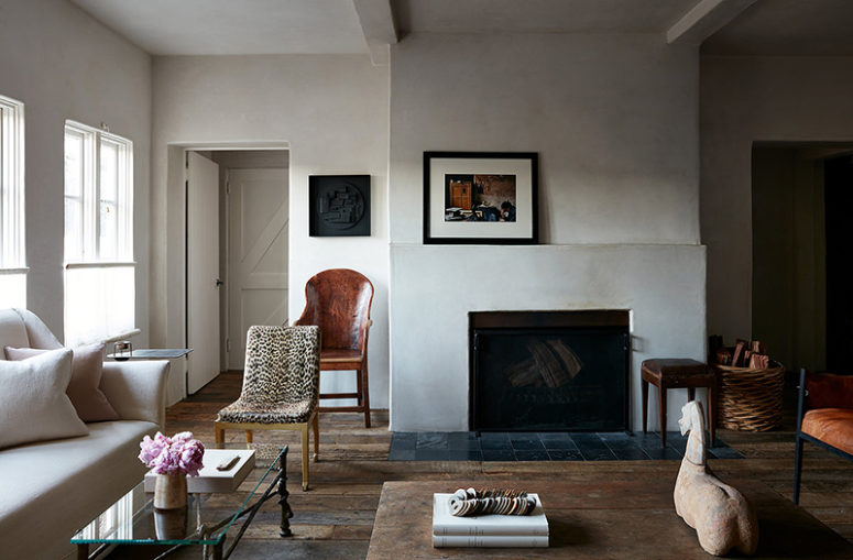 The walls are done with white plaster, the floor is of weathered wood, a fireplace adds coziness and baskets too