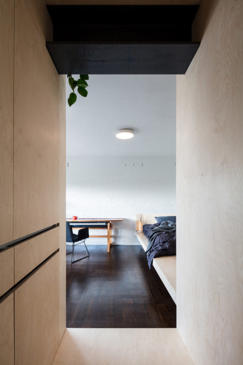 whitewashed brick wall in a small apartment The interest is added to the space with a white brick wall, dark wooden floors that contrast the light-colored plywood