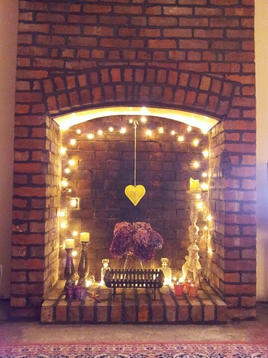 a fireplace with string lights, a hanging heart and some candles for a cute look