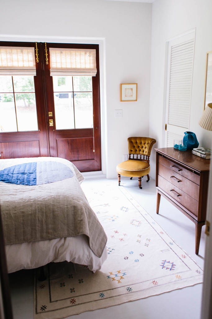 The next bedroom is done with french doors, boho textiles and vintage furniture