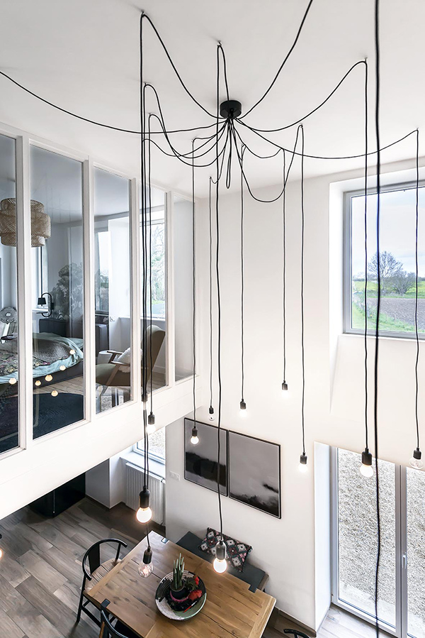 A modern and industrial chandelier highlights the height of the ceiling and brings more light to the bedroom above A modern and industrial chandelier highlights the height of the ceiling and brings more light to the bedroom above