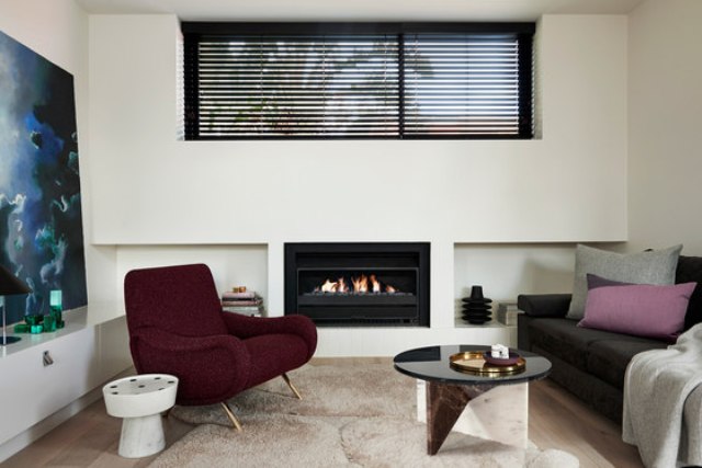 The living space is done with a comfy chair and sofa, a bold table on geometric stone legs and a built in fireplace The living space is done with a comfy chair and sofa, a bold table on geometric stone legs and a built-in fireplace
