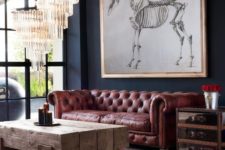 07 an eclectic space with a rough wooden beam table, glam crystal chandeliers and a brown leather Chesterfield sofa