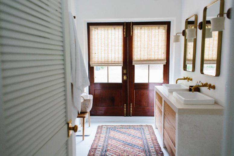 The bathroom features stone and wwood sink stands and various textiles
