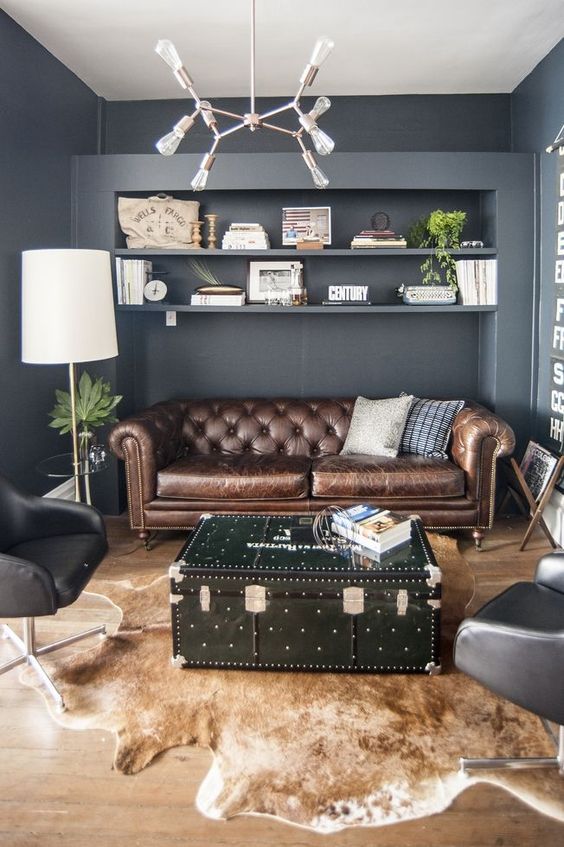 a brown leather Chesterfield and a black chest add an industrial touch to the space