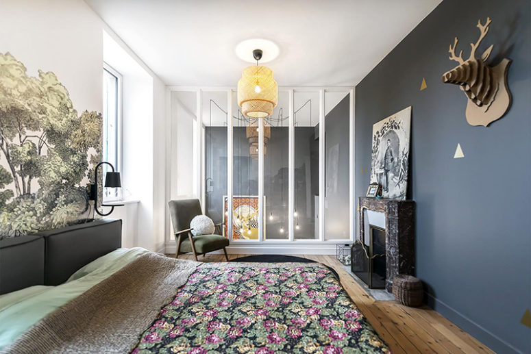 The master bedroom features a non-working fireplace, an upholstered bed and a floral headboard wall