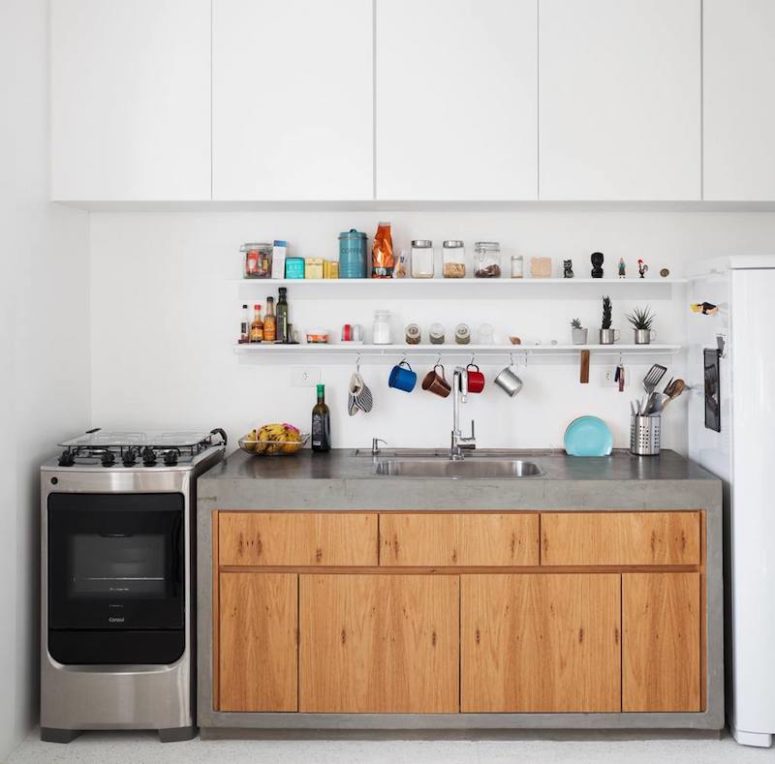 The kitchen is done with white upper cabinets and a wooden one clad with concrete, it's compact and comfortable