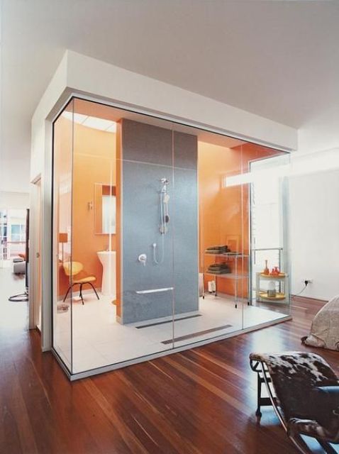 a modern glass-enclosed bathroom with orange and grey tiles right in the interior