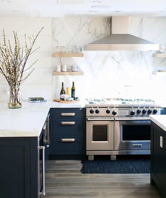 a navy kitchen with white marble countertops and a backsplash for a more elegant look