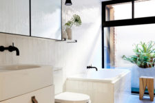 12 The bathroom is clad with creamy glossy tiles and accented with blacck details