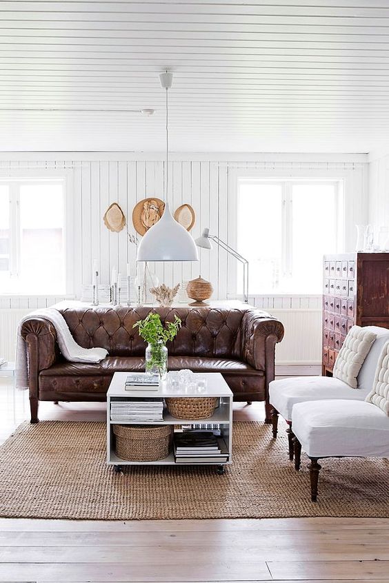 a modern farmhouse living room with vintage furniture and a brown leather Chesterfield