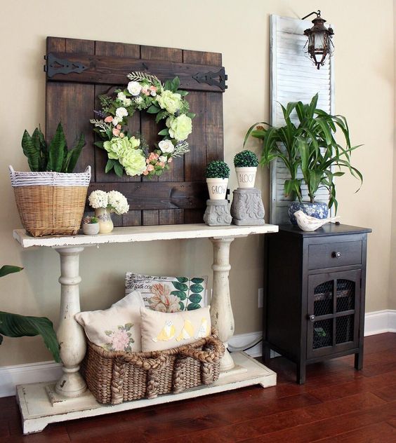 a barn door with a faux flowers and greeery wreath, potted succulents and boxwood for a chic look