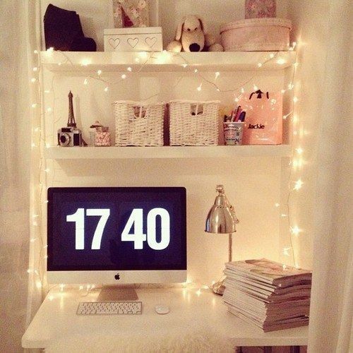 a small girlish workspace with string lights hanging on the shelves over it