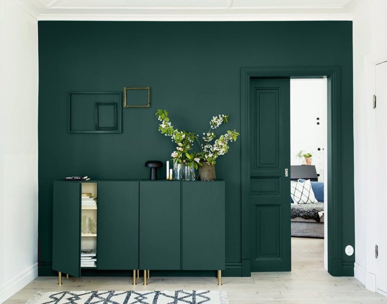 a dark green wall and a matching sideboard with brass legs to create a seamless look