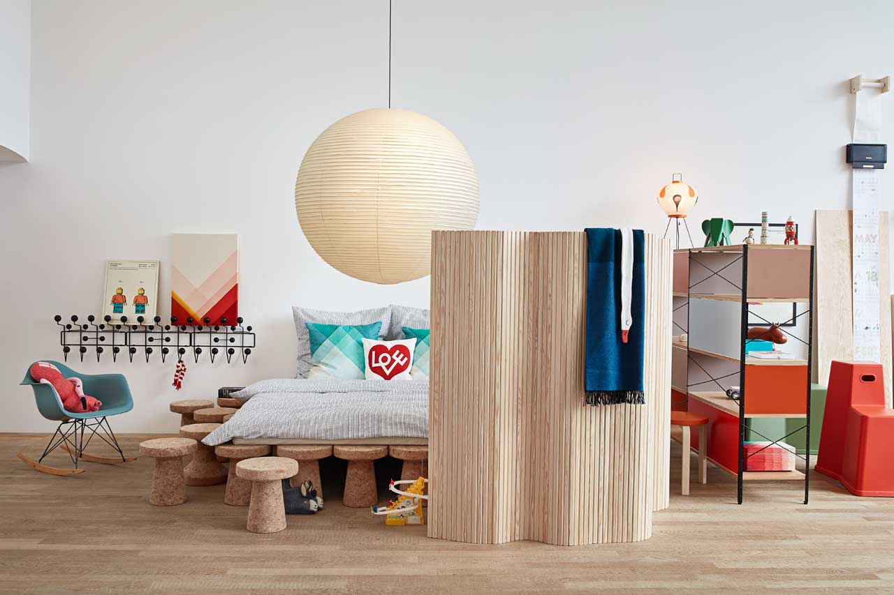 The bedroom is bold and bright, the bed is placed on cork stools, and there's much colorful furniture