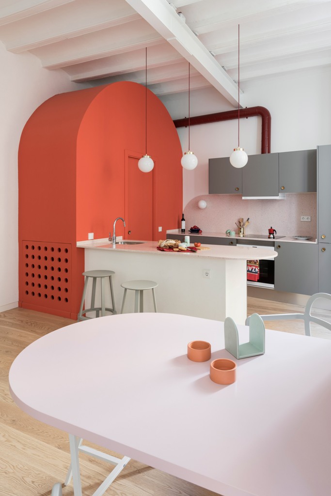 The kitchen is done with grey cabinets, there's an arched red unit with a toilet inside and rounded tables that echo with this unit The kitchen is done with grey cabinets, there's an arched red unit with a toilet inside and rounded tables that echo with this unit