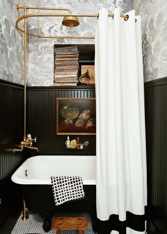 a vintage bathroom with a free-standing bathtub and black wainscoting that saves the walls form water