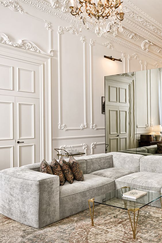 molded walls, ceiling and a glam chandelier combine with contemporary furniture and other touches