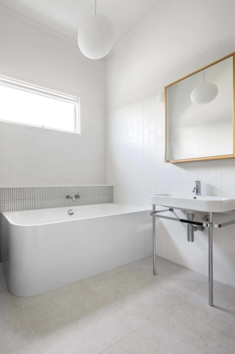 simple bathroom design with a free standing bathtub The bathroom is white and sleek, there's a free-standing bathtub, white tiles and a modern mirror