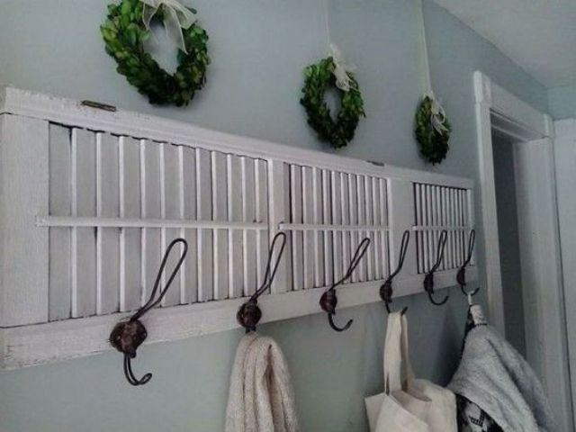 a coat rack made from an old shutter and greenery wreaths over it for a cute farmhouse feel