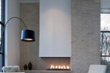 04 a refined asymmetric fireplace with a neutral brick wall and a sleek white hood is a focal point here