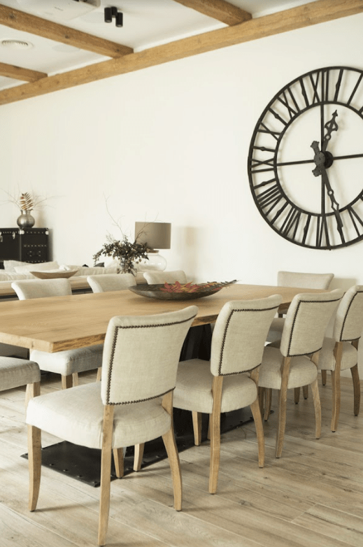 vintage clock used as wall decor The dining space is done with a wooden dining table, comfy upholstered chairs and a large vintage clock