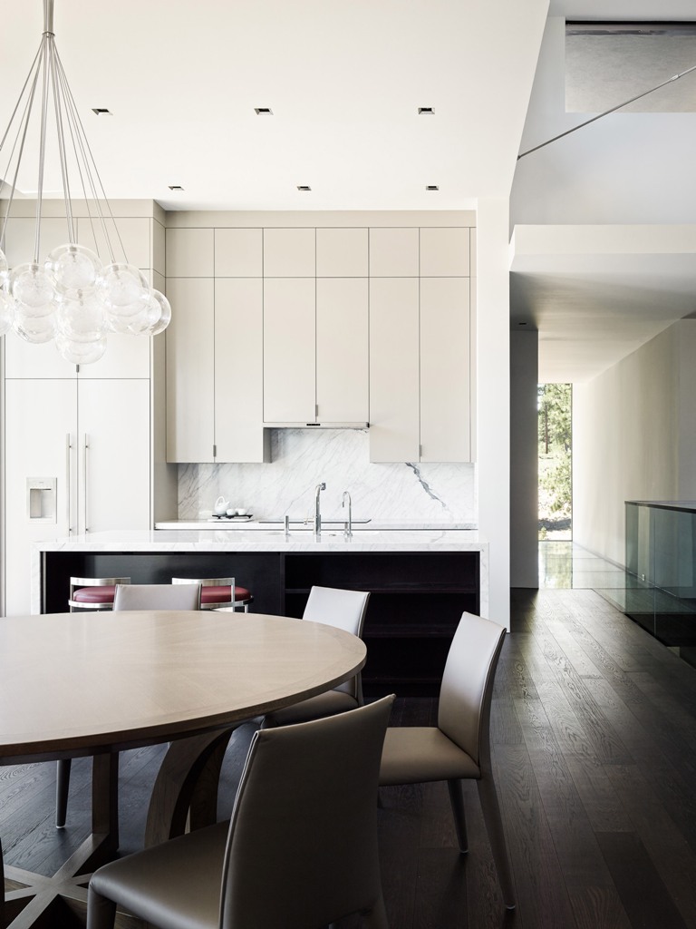 The kitchen and dining space are united, there are upper cabinets of different height, a marble backsplash and modern leather chairs The kitchen and dining space are united, there are upper cabinets of different height, a marble backsplash and modern leather chairs