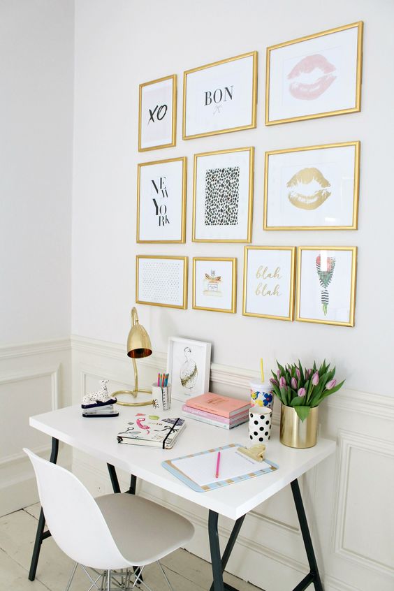 a girlish workspace with a gallery wall with gold frames and various girlish art