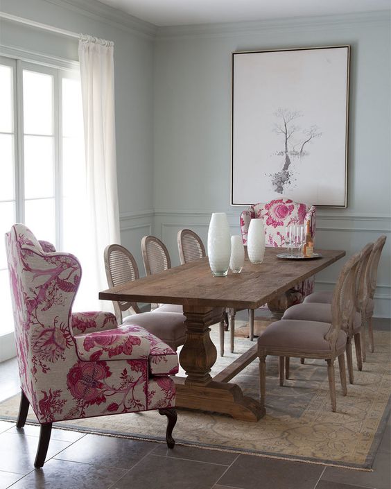 a vintage rustic dining room is spruced up with pink floral upholstery wingback chairs