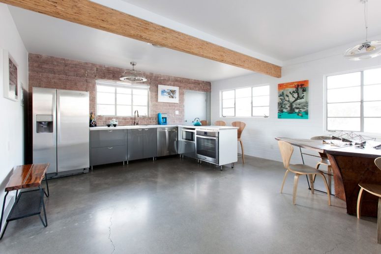 The kitchen and dining space comprise one space with wooden beams, an exposed brick wall and metal cabinets The kitchen and dining space comprise one space with wooden beams, an exposed brick wall and metal cabinets