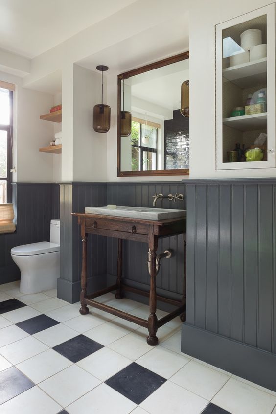 a farmhouse bathroom with graphite grey wainscoting that matches the floor tiles