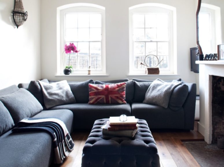 a small modern space with a large grey sectional sofa that creates a conversation pit with a fireplace