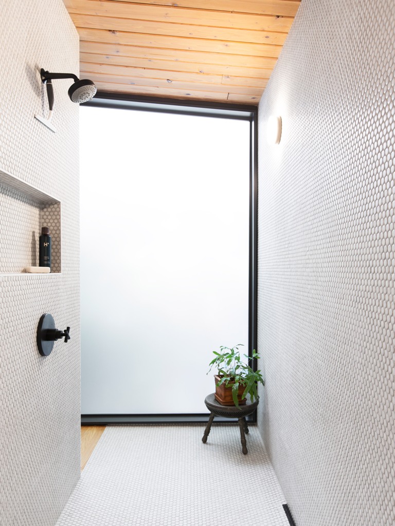 The bathroom is fully clad with penny tiles, there's opaque glass that lets light inside but keeps the space private The bathroom is fully clad with penny tiles, there's opaque glass that lets light inside but keeps the space private