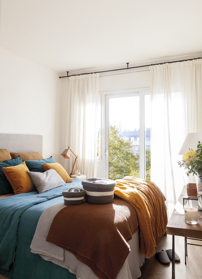 The master bedroom is decorated in contrasting and vivacious colors, there are layered textiles and cozy decor