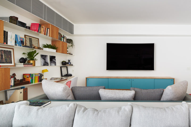 The living space is done with comfy grey sofas and a gorgeous wall unit that consists of thin open shelves