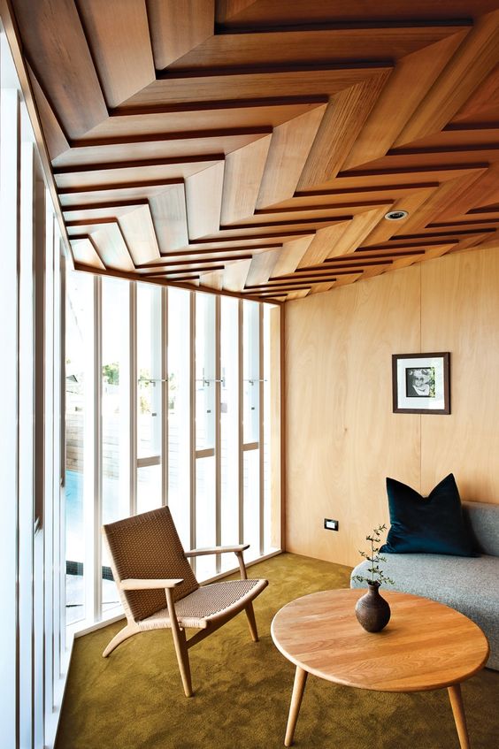 a catchy and sculptural wood chevron ceiling adds to this mid-century modern space