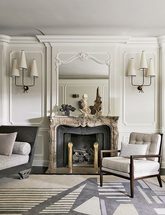 a creamy living room with molding, an antique fireplace and edgy designer's furniture and lamps